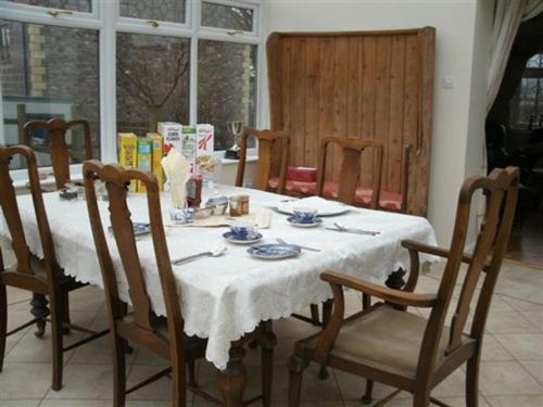 a dining room table with a white table cloth and chairs at Ebborways Farm Bed and Breakfast in Priddy