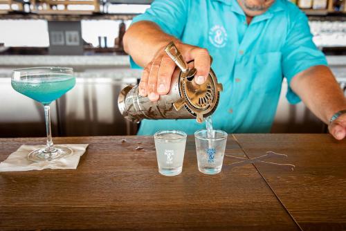 a man pouring a blue drink into a glass at Saba Rock Resort in Virgin Gorda