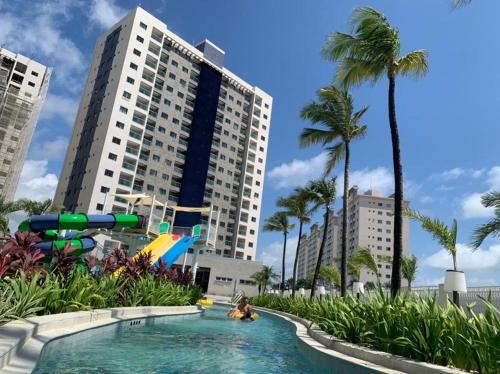 a pool at a resort with palm trees and buildings at Apartamento no Salinas Exclusive Resort in Salinópolis
