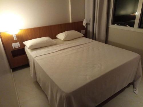 sypialnia z białym łóżkiem i oknem w obiekcie Apartamento no Salinas Exclusive Resort w mieście Salinópolis