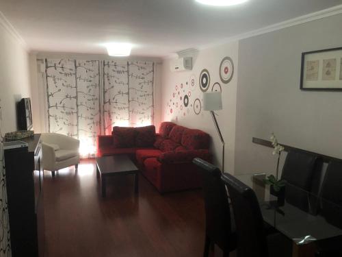 a living room with a red couch and a table at Apartamento Acueducto, tres dormitorios y parking gratis in Mérida