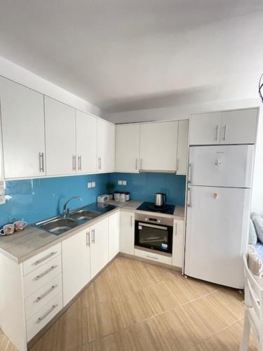 a kitchen with white cabinets and a sink and a refrigerator at Marena 1 in Makry Gialos