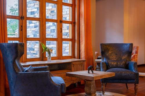 two chairs and a table in a room with windows at Chimpundu Lodge in Fort Portal