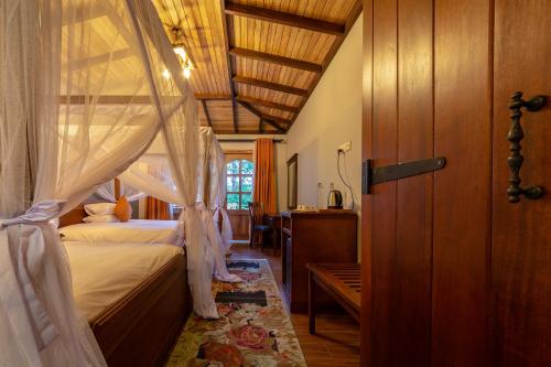 - une chambre avec un lit à baldaquin dans l'établissement Chimpundu Lodge, à Fort Portal