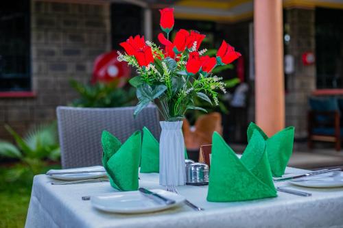 a table with a vase of red flowers on it at Lovely Garden Guest Home in Kisumu