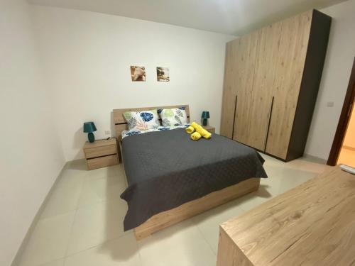 ein Schlafzimmer mit einem Bett mit einem gelben ausgestopften Tier darauf in der Unterkunft Sunshine Apartments Mellieha - modern three bedroom ground floor apartment with yard in Mellieħa