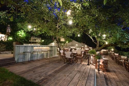 a wooden deck with tables and chairs under a tree at Vikos Hotel in Monodendri