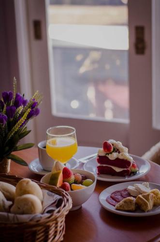 een tafel met borden en een glas sinaasappelsap bij Pousada Lanai Gramado in Gramado