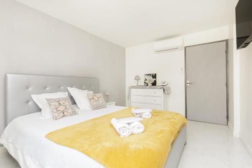 - une chambre blanche avec un grand lit et des serviettes dans l'établissement Cosy YourHostHelper, à Cannes