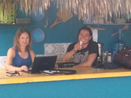 a man and a woman sitting at a table with a laptop at Hostal Jardin in Mahahual