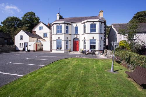 uma grande casa branca com uma porta vermelha em Burford Lodge Guest House em Ardglass