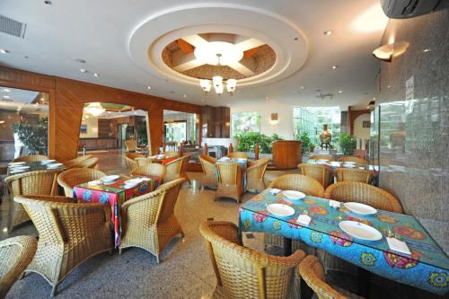 ein Restaurant mit Tischen, Stühlen und einem Kronleuchter in der Unterkunft Kenting Holiday Hotel in Altstadt von Hengchun