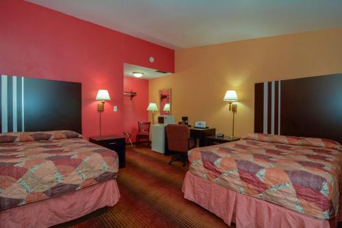 Rodeway Inn MacArthur Airport في رونكونكوما: سريرين في غرفة الفندق بجدران حمراء