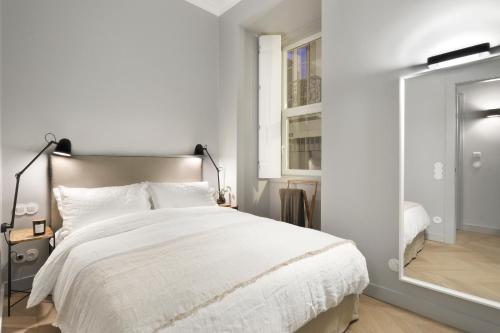 een witte slaapkamer met een groot bed en een spiegel bij Prime Lisbon - Boavista 44 in Lissabon
