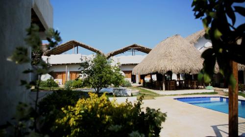 ein Resort mit einem Pool und einem strohgedeckten Gebäude in der Unterkunft Casa Dibulla Hotel Boutique in Dibulla