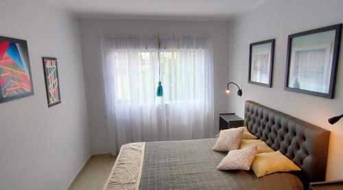 1 dormitorio con cama con almohadas y ventana en Apart Polonia II en San Miguel de Tucumán