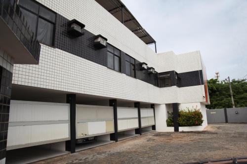 un edificio de ladrillo blanco con aparcamiento en Piramide Stella Maris Adults Only en Salvador