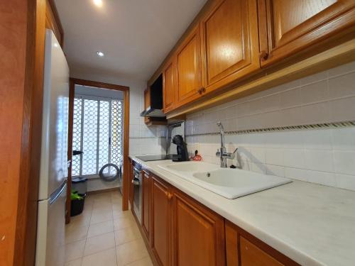 a kitchen with wooden cabinets and a sink at Mirando al mar in Playa de Xeraco