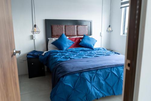 een slaapkamer met een blauw bed met blauwe kussens bij Departamento La Choza Central Pool in GDL downtown in Guadalajara