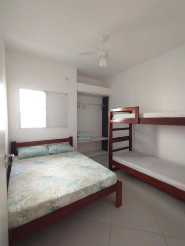 a bedroom with a bed and two bunk beds at Villagio Aloha Beach in Bertioga