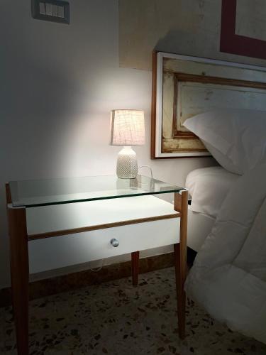 a glass table with a lamp on it next to a bed at Il giardino di Iole Via Giovanni Amendola n36 in Sassari