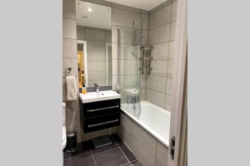 a bathroom with a tub and a sink and a bath tub at Luxury 1 Bedroom Apartment with Netflix & Parking in Borehamwood