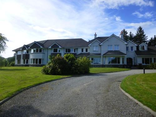 a large white house with a driveway at Loch Lein Country House in Killarney