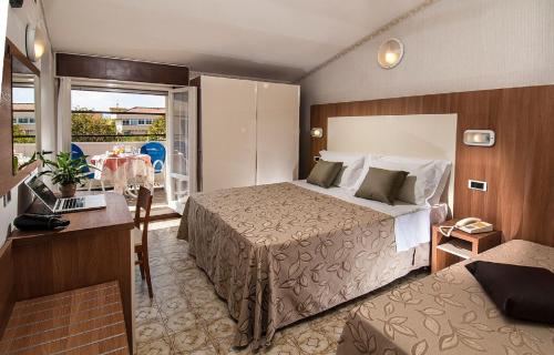 a hotel room with a bed and a table with a laptop at Hotel Lina in Misano Adriatico