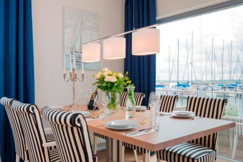 ハイリゲンハーフェンにあるOstsee - Maisonette - Appartement Nr 54 "Marina-Blick" im Strand Resortのダイニングルーム(椅子、大きな窓付)