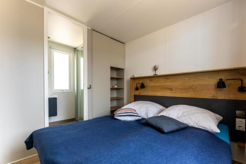 ein Schlafzimmer mit einem blauen Bett mit zwei Kissen in der Unterkunft Muschel 61 in Scharbeutz