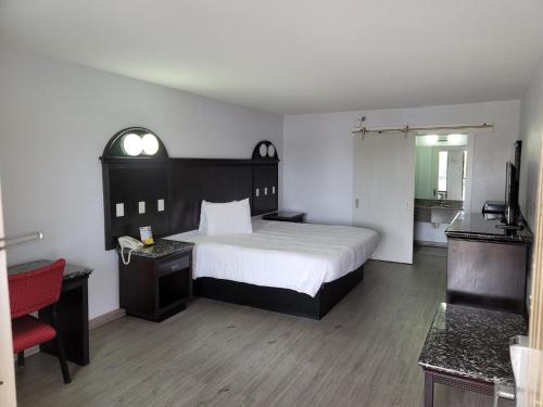 a bedroom with a large bed and a red chair at Fairway Inn in Fort Walton Beach