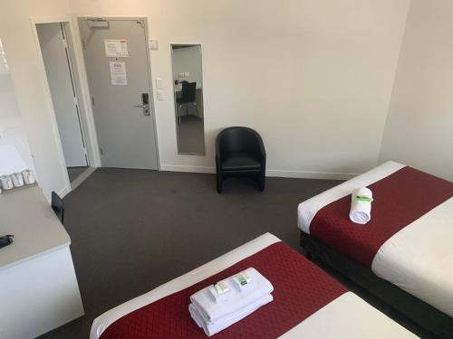 a hotel room with two beds and a chair at George Williams Hotel in Brisbane