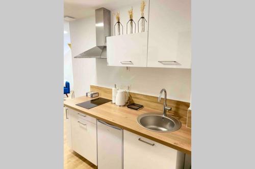 a kitchen with white cabinets and a sink at Studio moderne au cœur de Reims in Reims