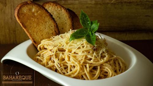a bowl of pasta with bread and a sprig of basil at Poza Clara Sanctuary in Bacalar