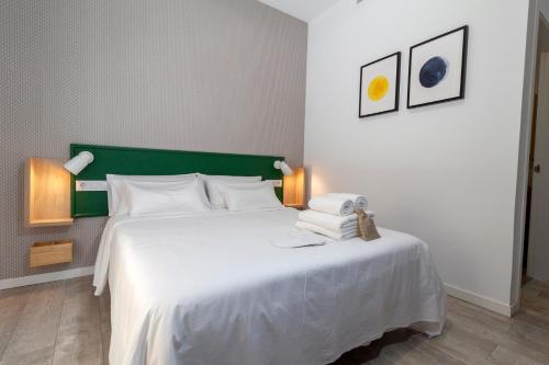 a bedroom with a large white bed with a green headboard at Hostal Casa de Luna y Sol in Úbeda