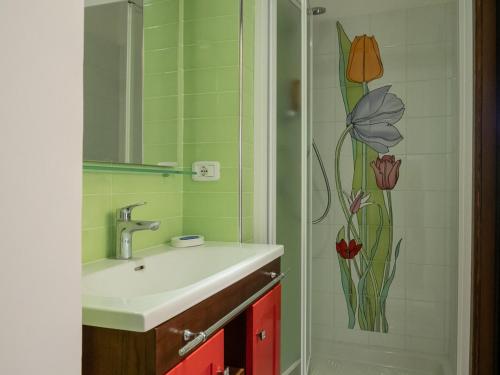 baño con lavabo y ducha con una flor en la pared en Casa Marietta, en San Nico