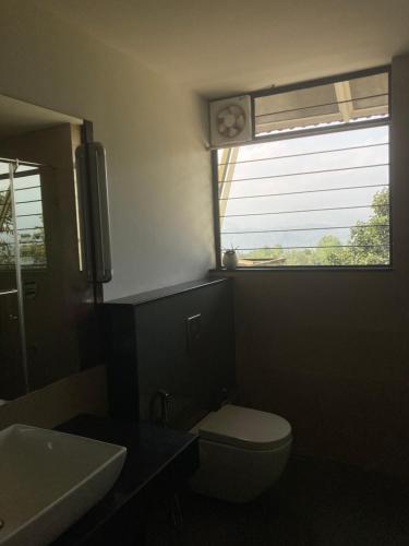 a bathroom with a toilet and a window with a clock at Homestay Namaha in Meppādi