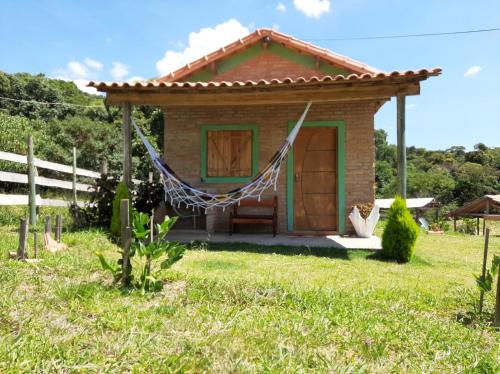 a small house with a hammock in a yard at Chalés e Camping Taquaral in São Thomé das Letras