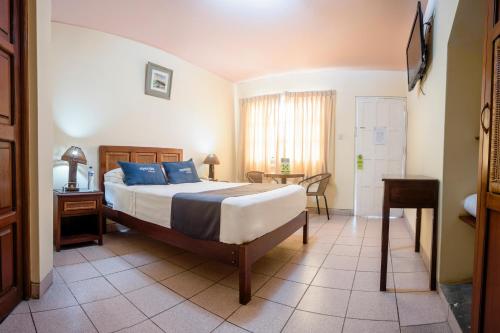Un dormitorio con una cama con almohadas azules y una mesa. en Las Palmeras de Huanchaco en Huanchaco