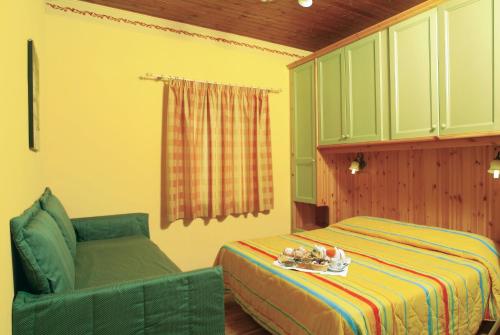 - une chambre avec un lit et une chaise verte dans l'établissement Club Hotel Lo Sciatore, à San Massimo