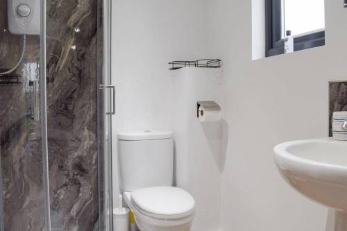 a white bathroom with a toilet and a sink at Secluded Log Cabin in beautiful private gardens 