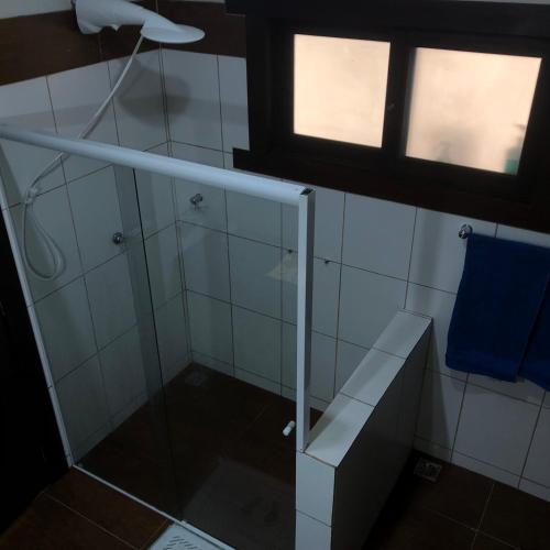 a bathroom with a glass shower with a blue towel at Pousada Vertente das Águas in Lumiar