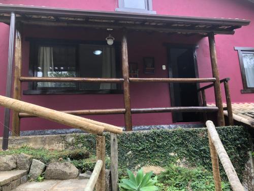 a wooden fence in front of a pink house at Pousada Vertente das Águas in Lumiar