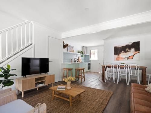 a living room with a couch and a tv at The Bach in Byron in Byron Bay