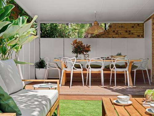 a patio with a table and chairs on a deck at The Bach in Byron in Byron Bay