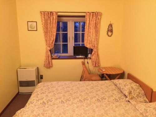 a bedroom with a bed and a window at Pension Rapport in Tambara Plateau in Numata