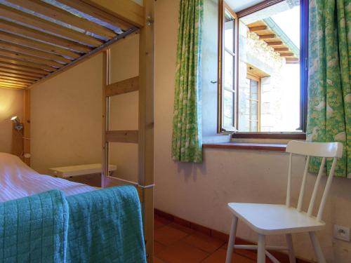 ein Schlafzimmer mit einem Bett, einem Fenster und einem Stuhl in der Unterkunft La petit Gapard in Issac
