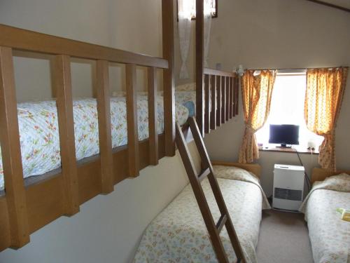 a bedroom with two bunk beds and a desk at Pension Rapport in Tambara Plateau in Numata