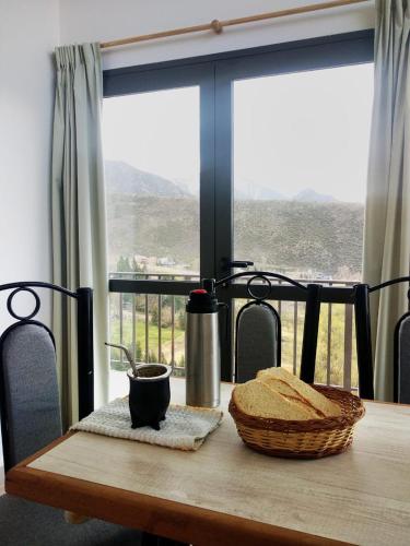 Una mesa de madera con una cesta de pan y una ventana. en El Mirador, en Potrerillos