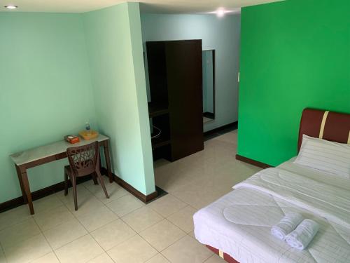 a bedroom with a green wall and a bed and a table at Myoldhouse in Lahad Datu